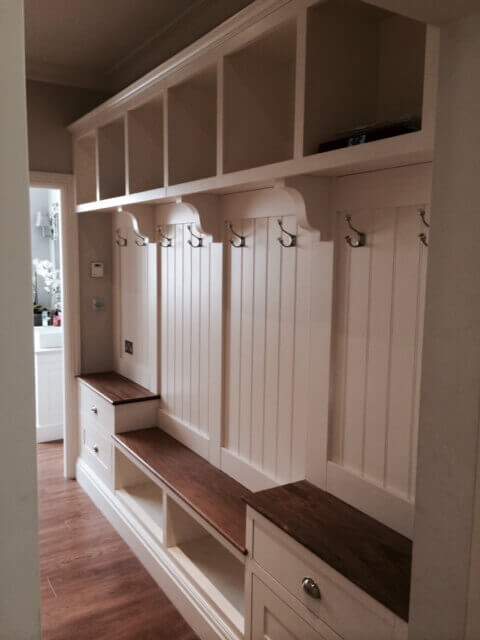 A hallway with lots of shelves and hooks on the wall