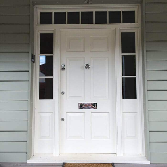 A white door with a mailbox on it is on a house.