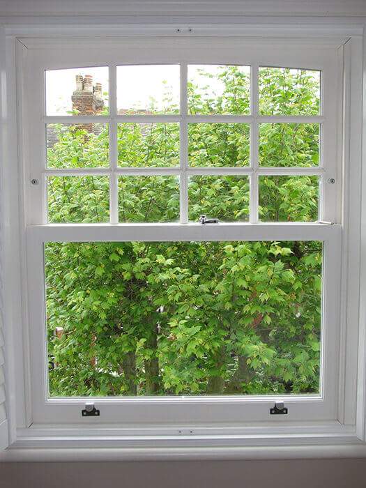 A white window with a view of trees in the background.