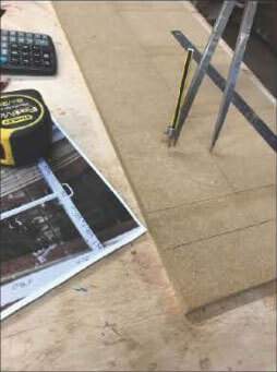 A tape measure , compass , and calculator are on a wooden table.
