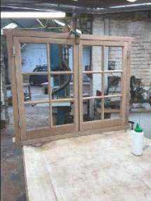 A wooden window is sitting on top of a wooden table in a workshop.