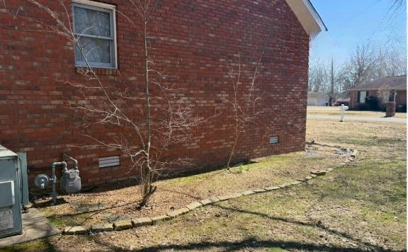 Red brick building exterior with a small tree and a grassy yard.