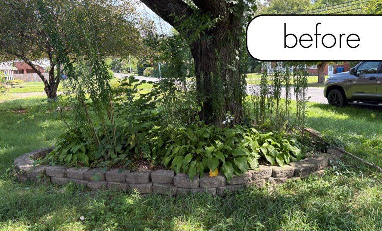 A brick building with a black lantern next to a white fence and a small garden on a sunny day.
