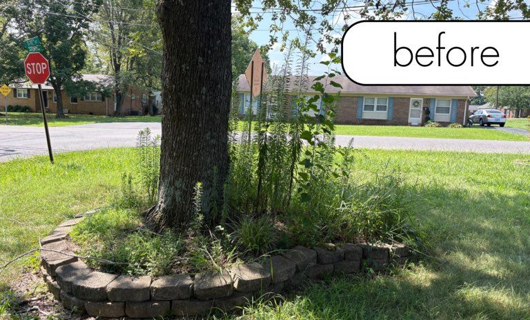 A brick building with a black lantern next to a white fence and a small garden on a sunny day.