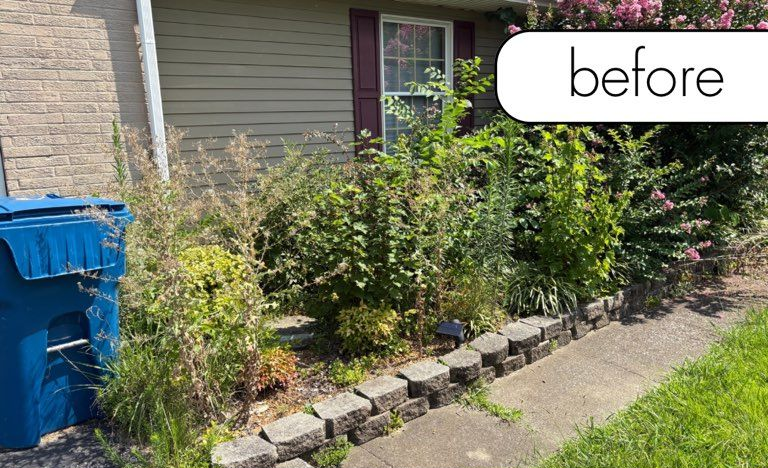 A brick building with a black lantern next to a white fence and a small garden on a sunny day.