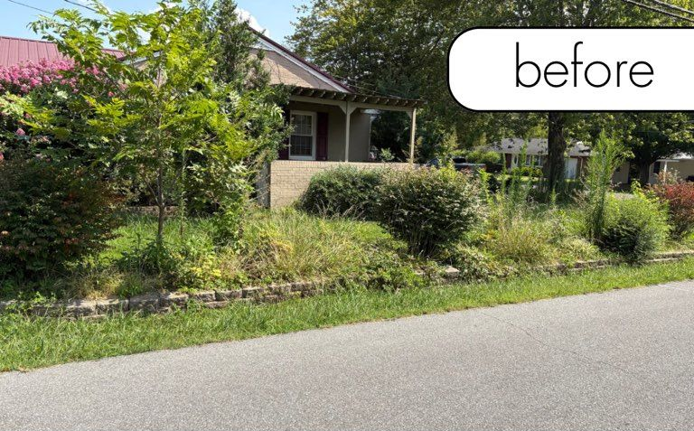 A brick building with a black lantern next to a white fence and a small garden on a sunny day.