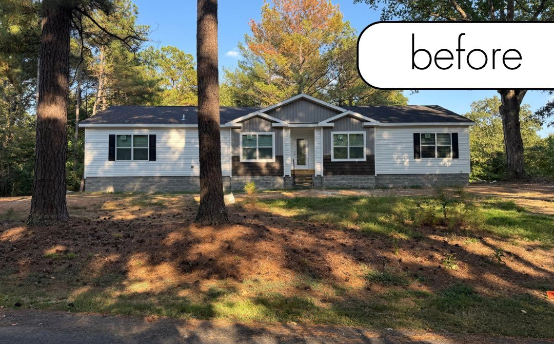A brick building with a black lantern next to a white fence and a small garden on a sunny day.