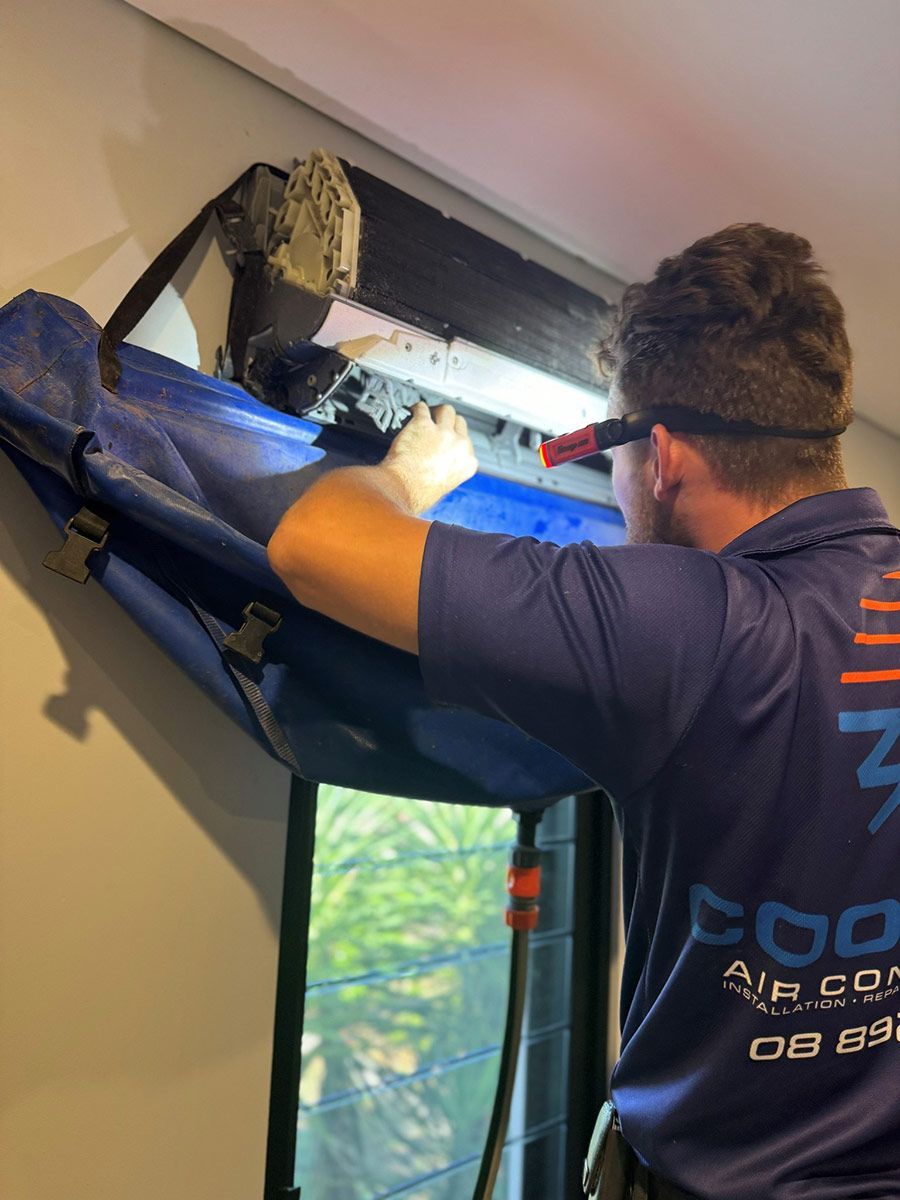 A Man In A Blue Shirt Is Working On An Air Conditioner — COOLIT NT In Berrimah, NT