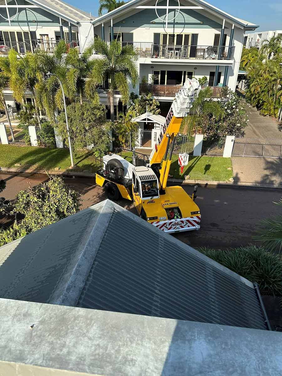 A Large Yellow Crane Is Parked In Front Of A Large House — COOLIT NT In Palmerston, NT