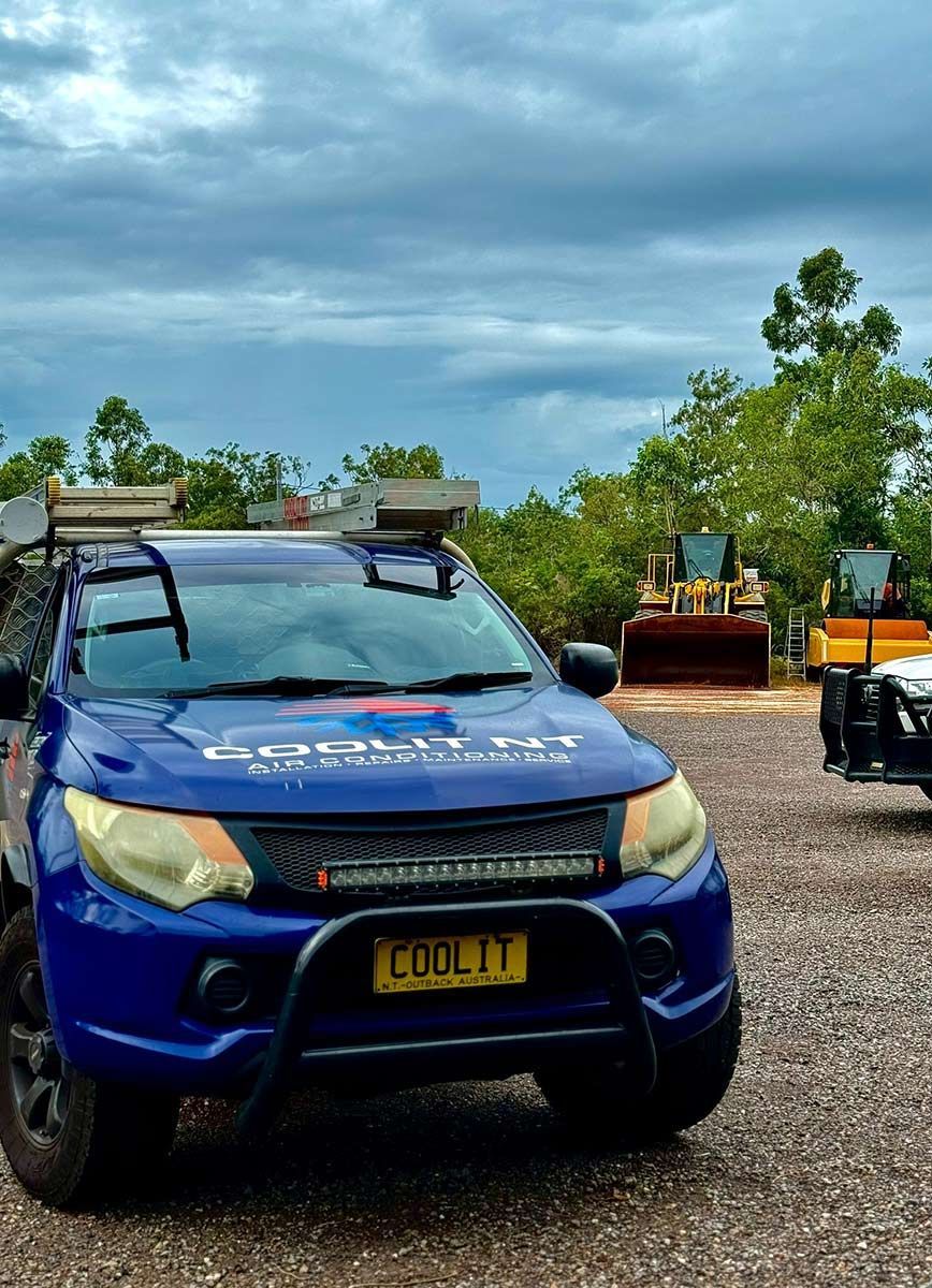 A Blue Truck Is Parked In A Gravel Lot Next To A Bulldozer — COOLIT NT In Berrimah, NT