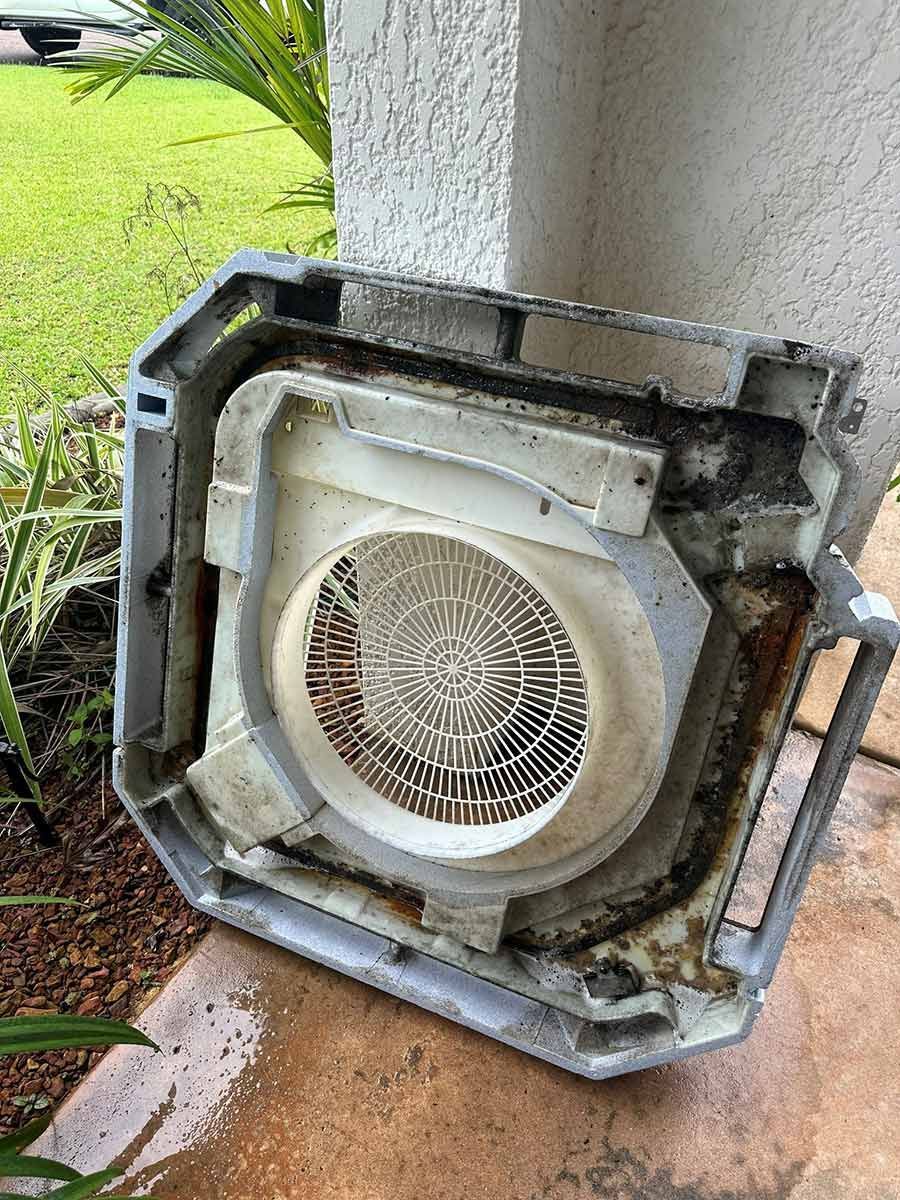 A Dirty Air Conditioner Is Sitting On The Ground Next To A Wall — COOLIT NT In Humpty Doo, NT