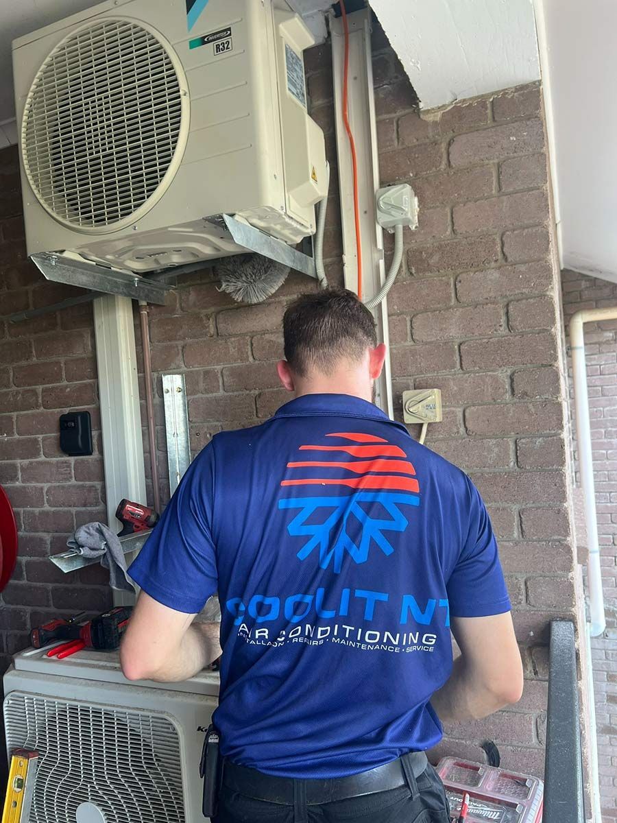 A Man In A Blue Shirt Is Working On An Air Conditioner — COOLIT NT In Berrimah, NT