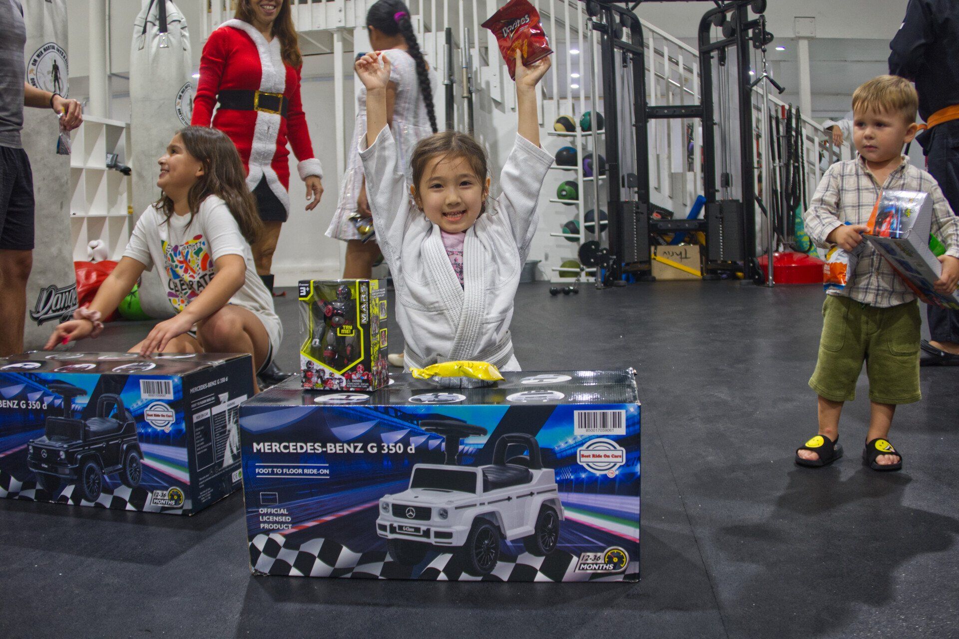 girl smiling because she won a toy MERCEDES-BENZ G 350 d at the American Top Team Aventura/NMB 2022 Christmas Toy Drive