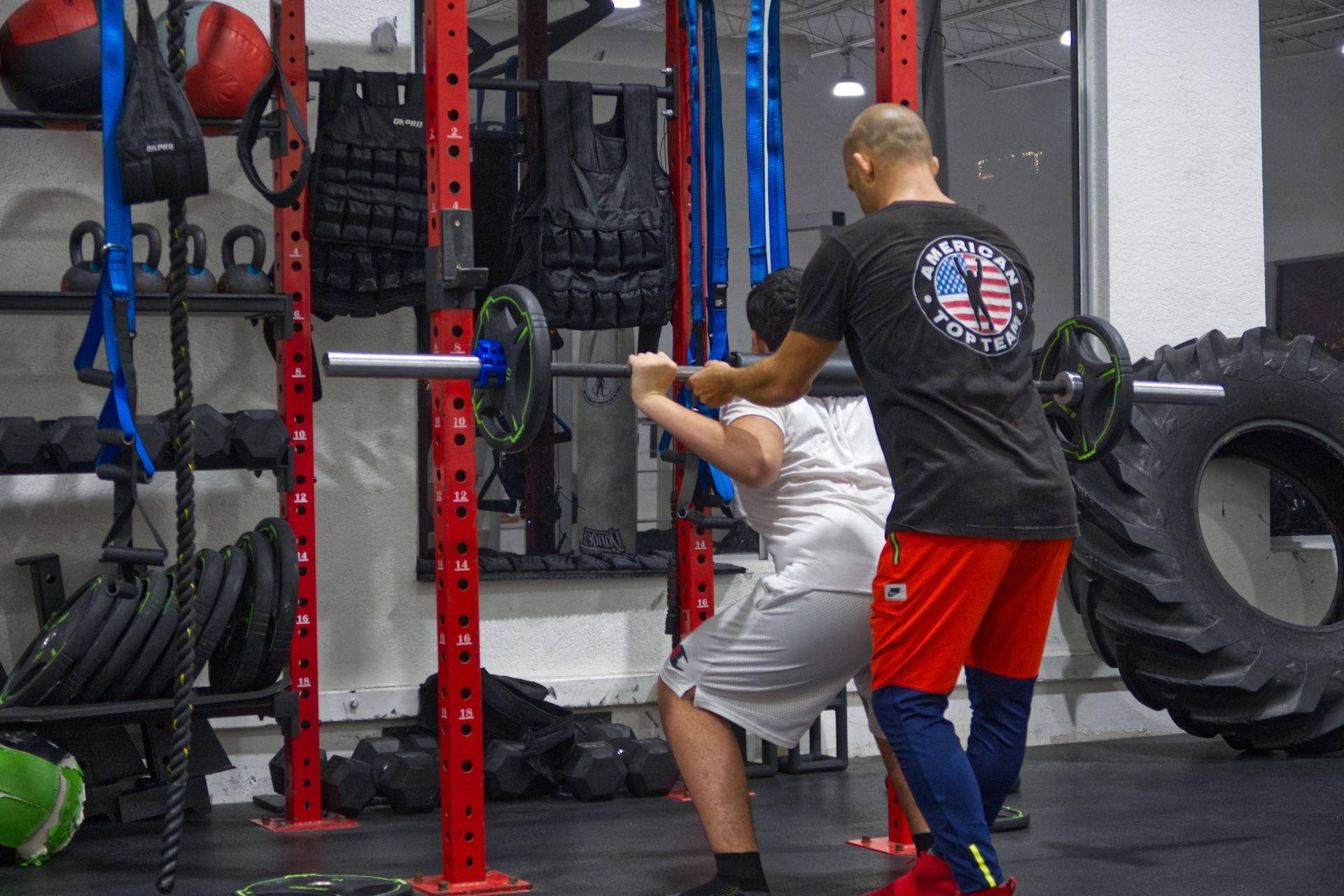 Coach Ivan helping a youth student squat at American Top Team Aventura/NMB