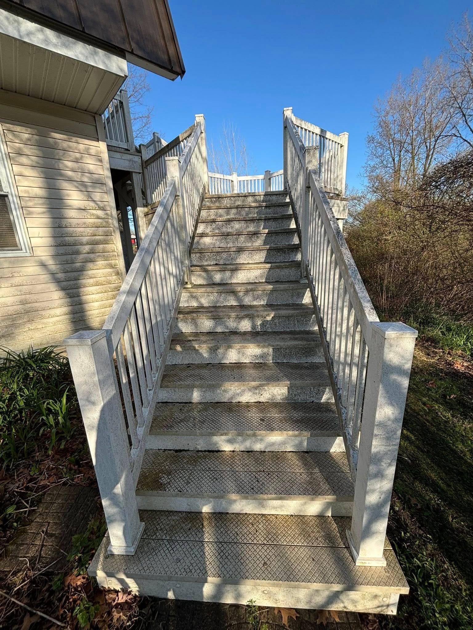A set of stairs leading up to a house with a white railing.