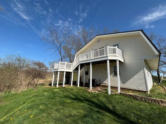 A white house with a large deck on top of it.