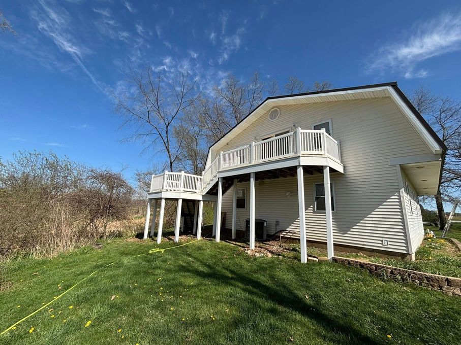 A white house with a large deck on top of it.