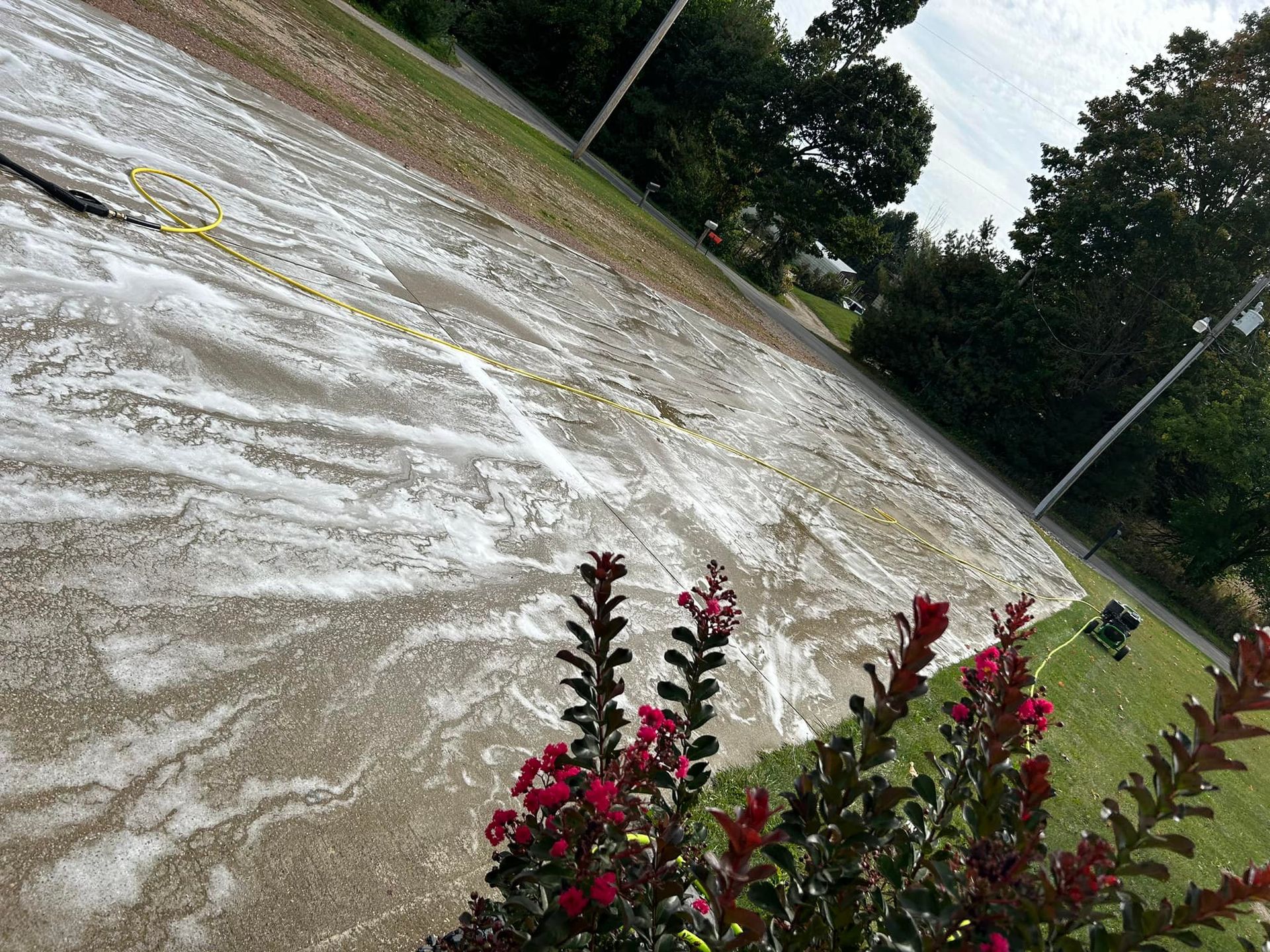 A person is cleaning a driveway with a pressure washer.