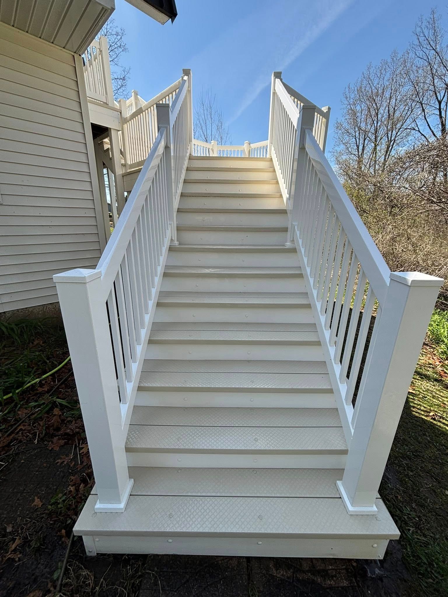 A set of stairs leading up to a house with a white railing.