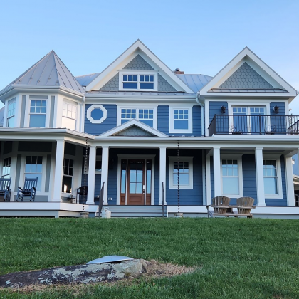 Blue house with white trim and gray roof; lawn in foreground.