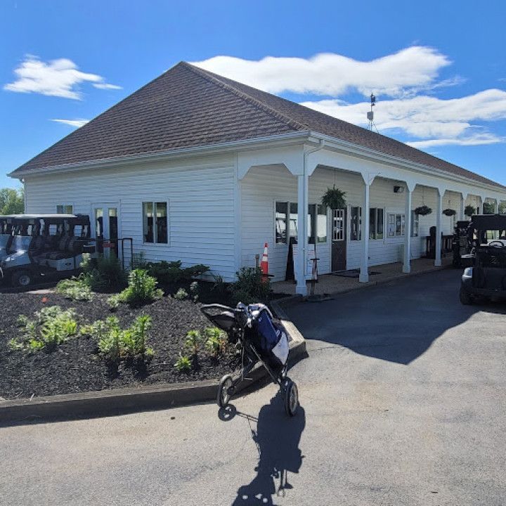 White golf clubhouse with a cart and golf carts on a sunny day.