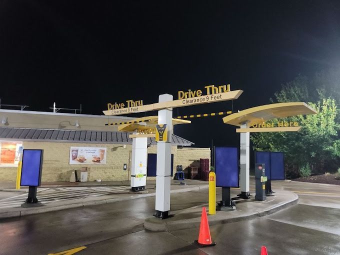 McDonald's drive-thru at night; several ordering kiosks, lit signs, and yellow canopies.