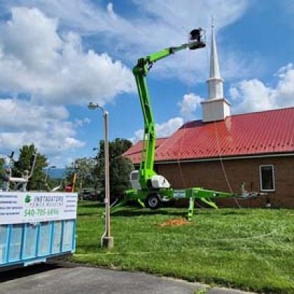 Green lift reaching towards church steeple; truck with company name in the foreground.