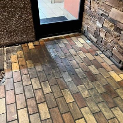 Brick entryway with dark door and tan, brown, and gray bricks.