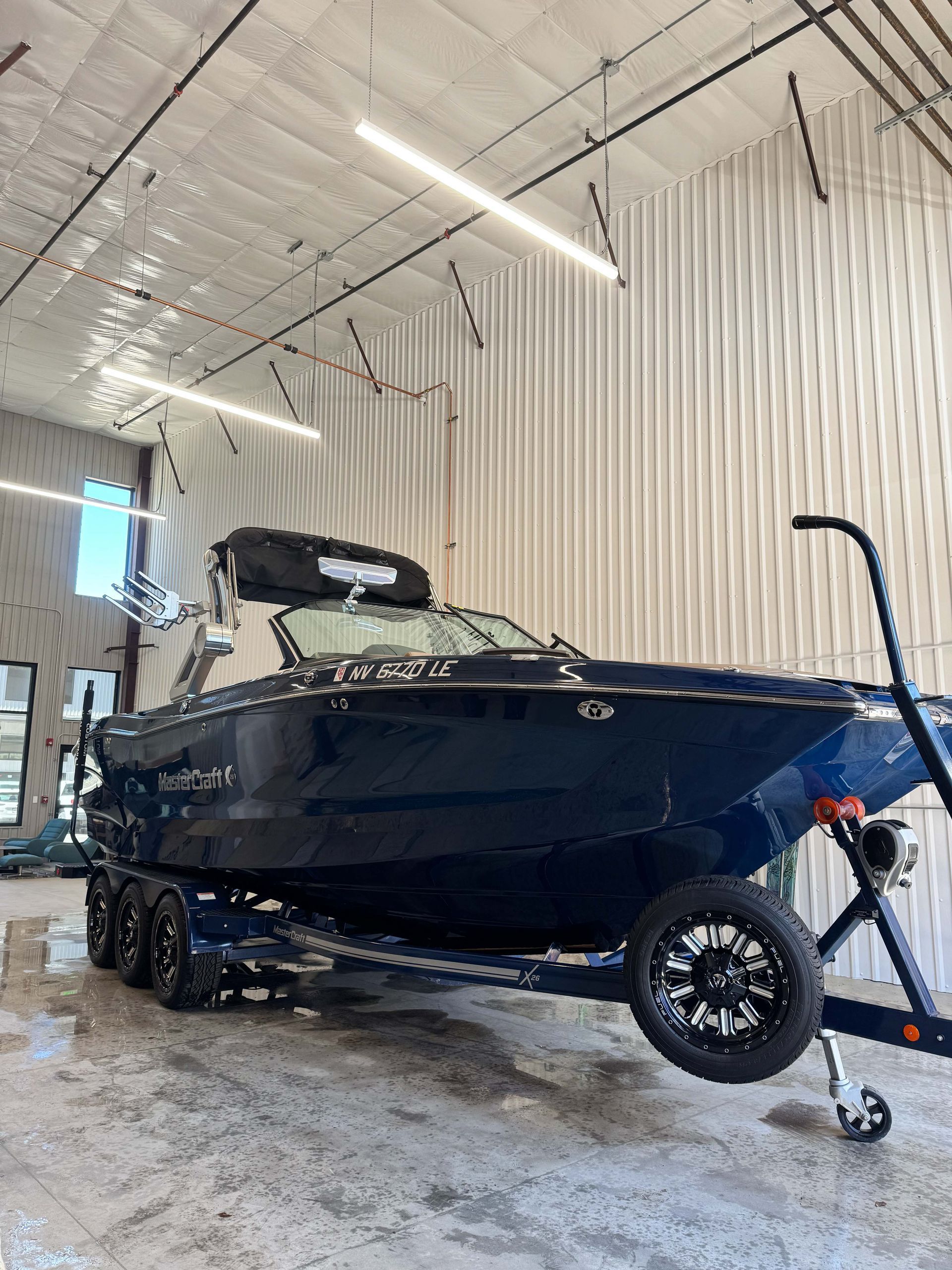 Dark blue boat on a trailer inside a brightly lit warehouse.