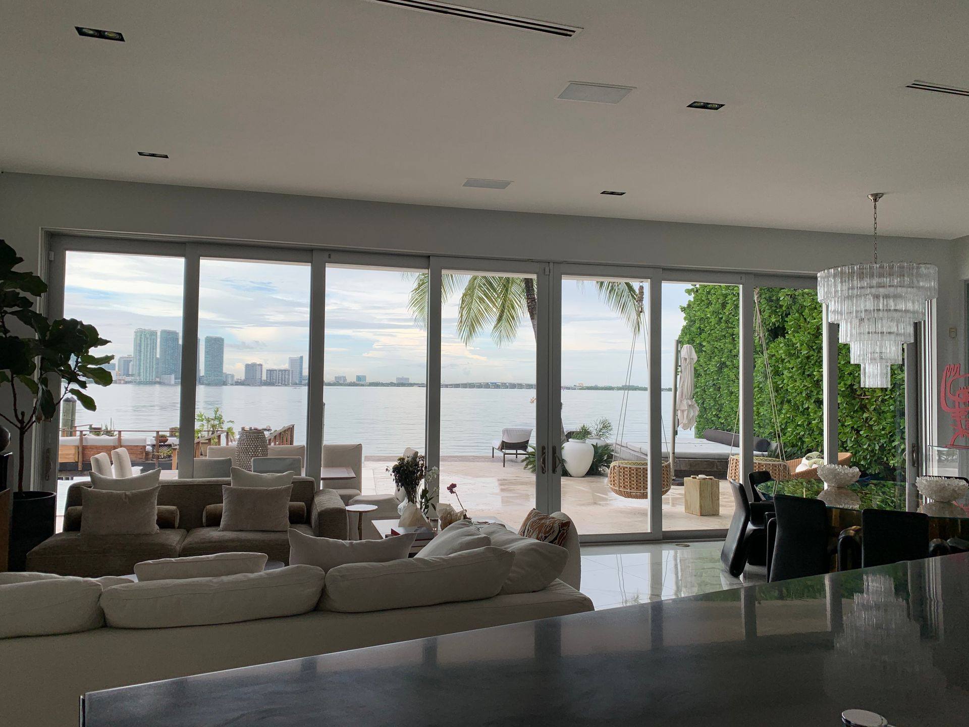 Luxurious waterfront living room with large sliding doors, overlooking a city skyline.