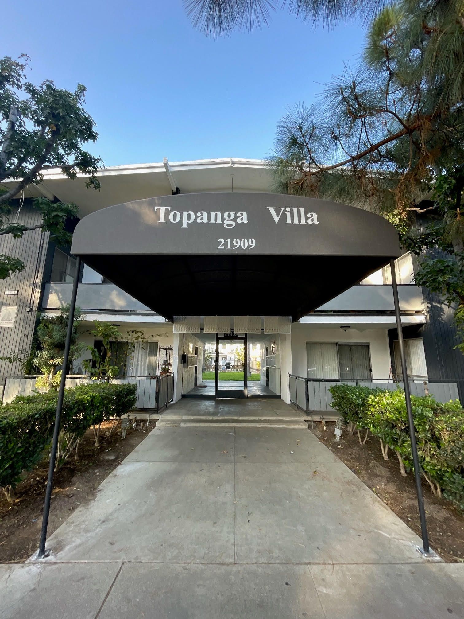 Topanga Villa apartment building entrance with black awning, address 21969, and concrete walkway.