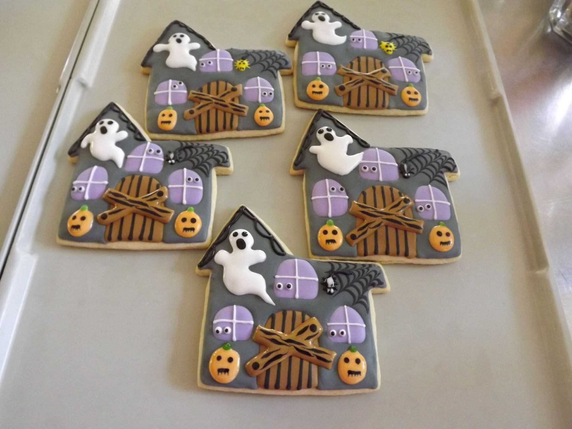 The cookies are decorated to look like haunted houses with ghosts and pumpkins