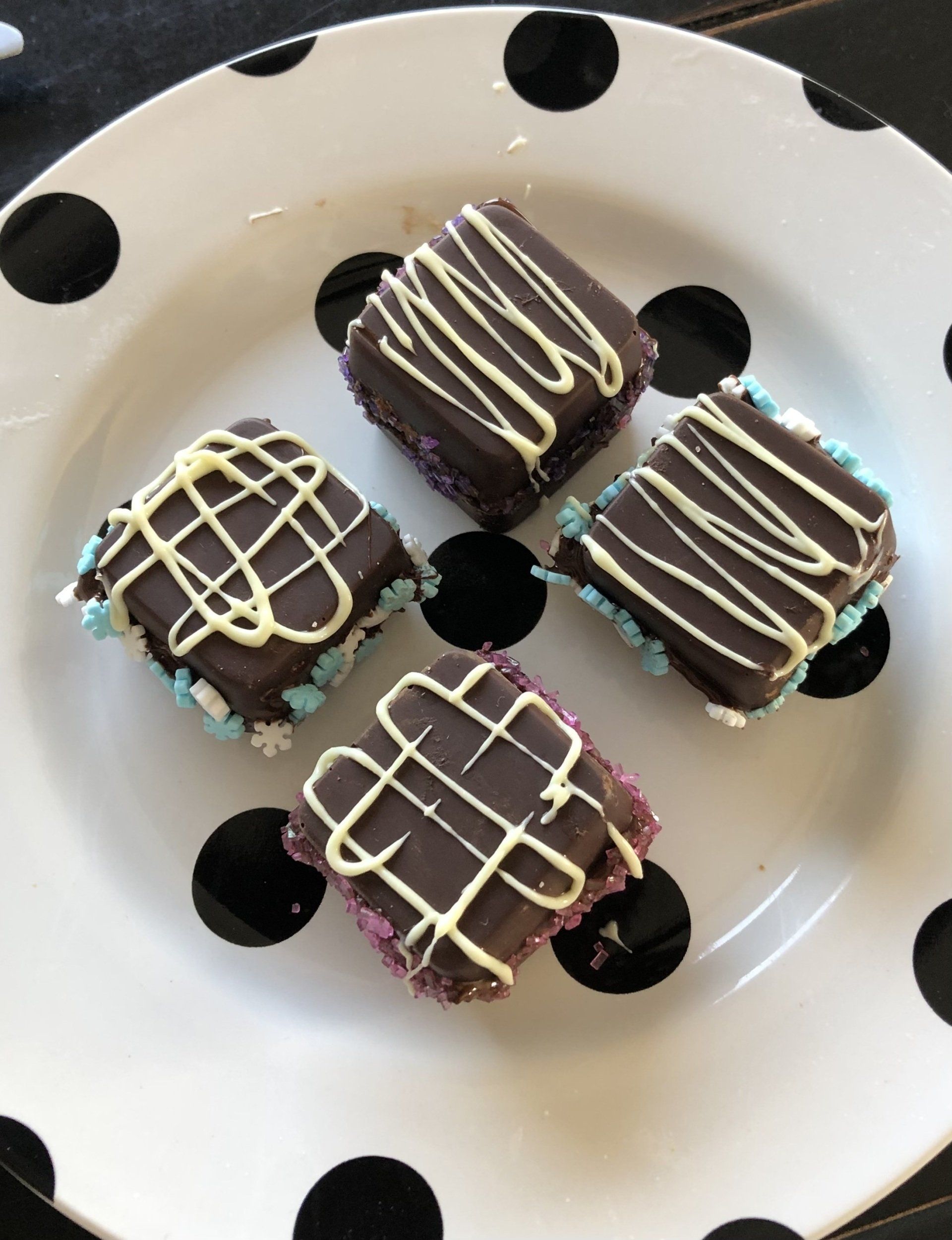 Four chocolate squares on a black and white polka dot plate