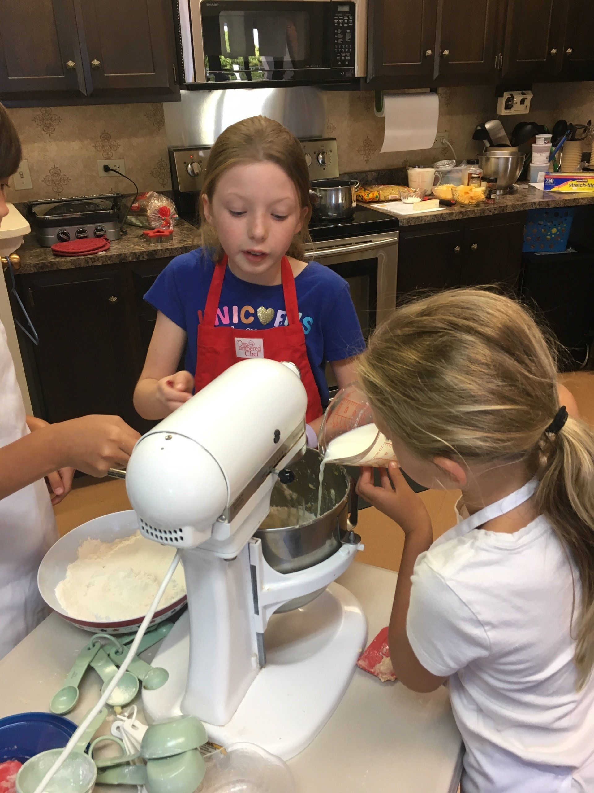A group of young girls are using a mixer in a kitchen.