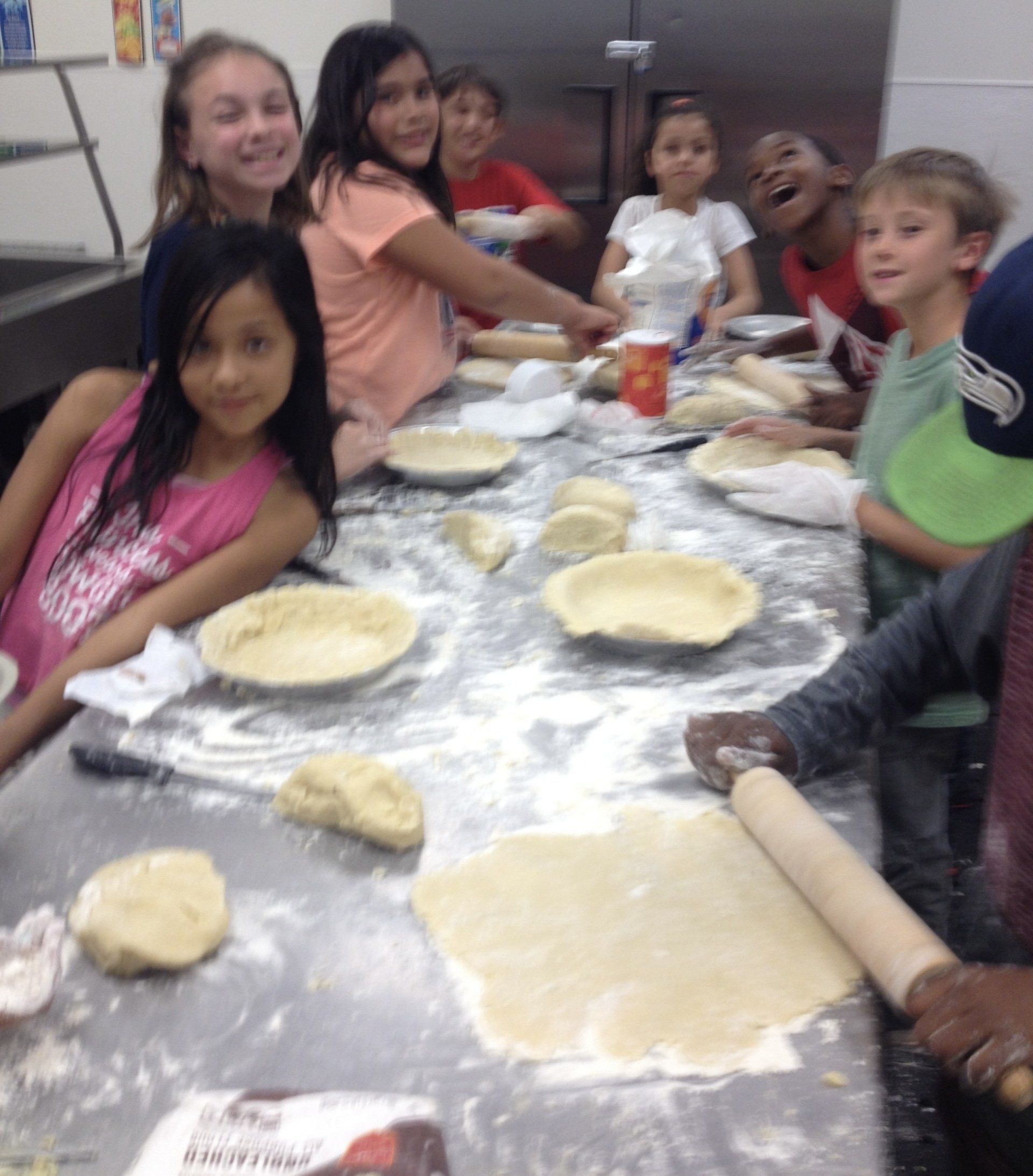 A group of children are sitting around a table with plates and dough
