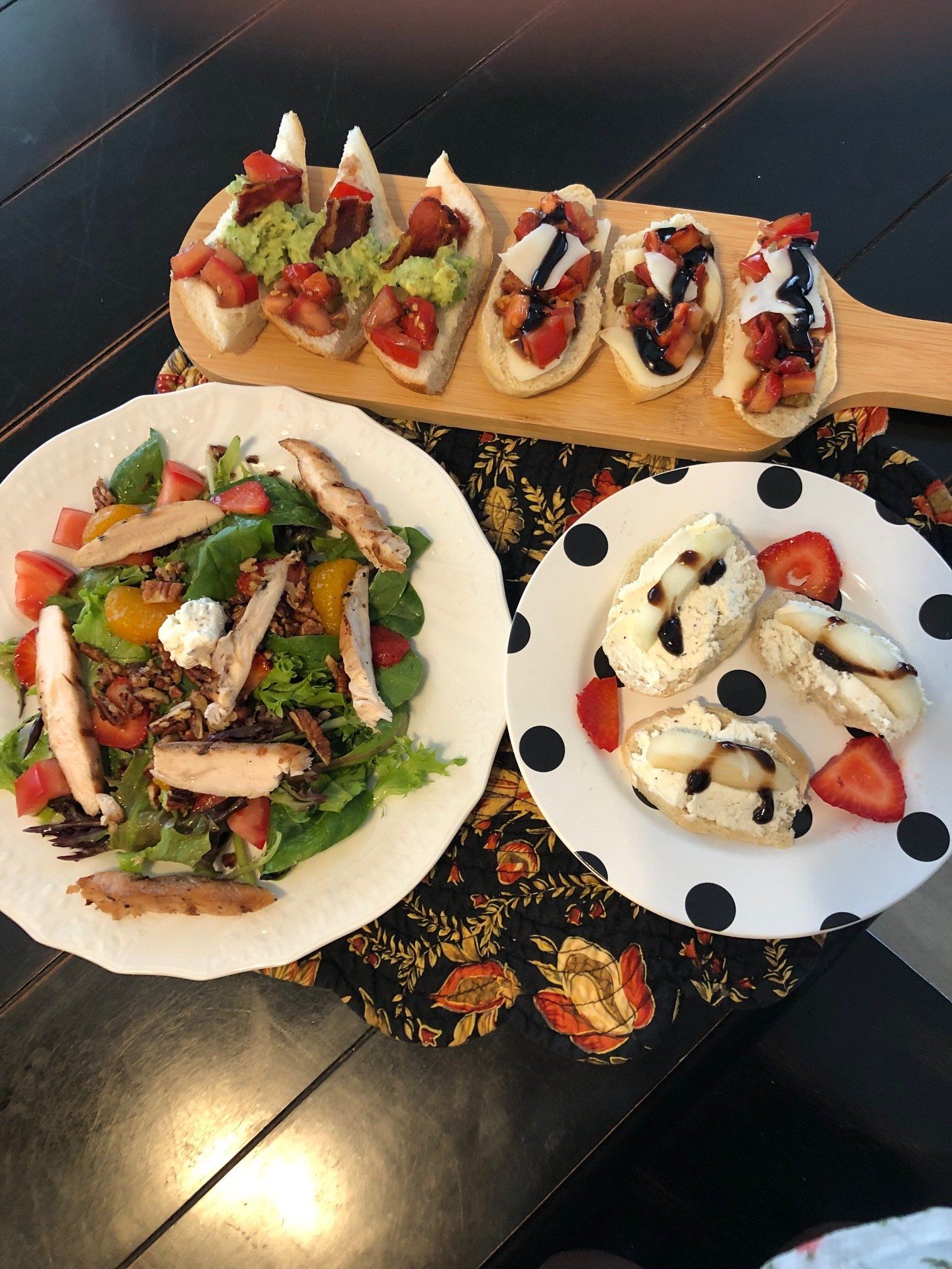 Three plates of food are sitting on a table including a salad and appetizers.