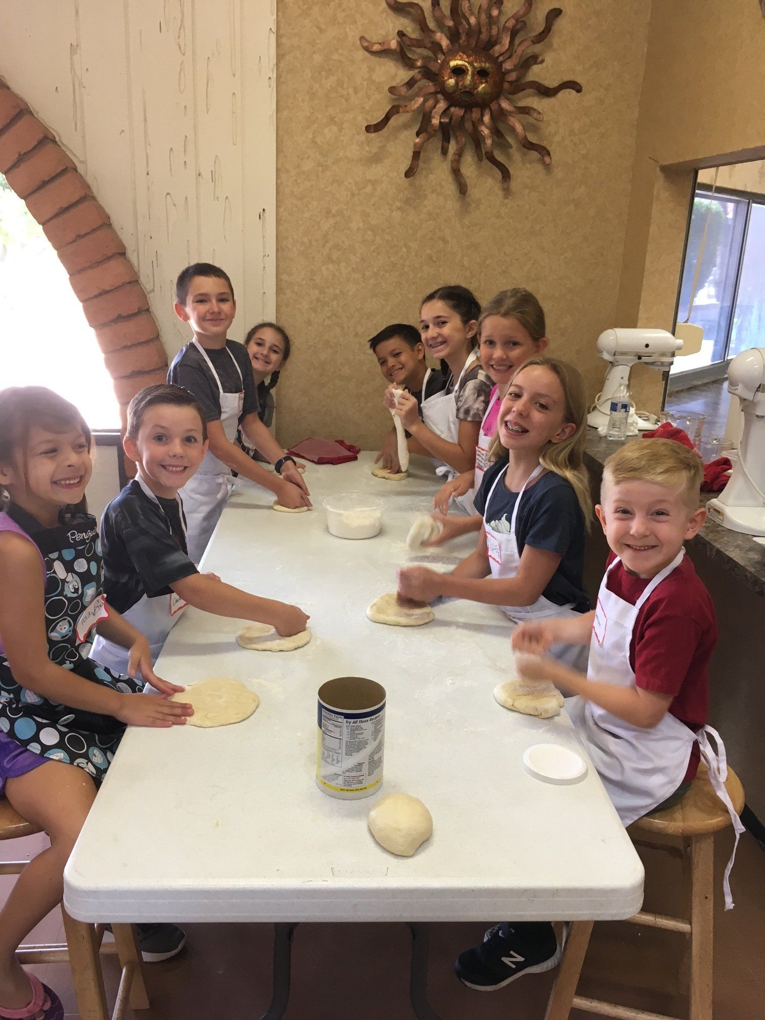 A group of children are sitting at a table kneading dough.