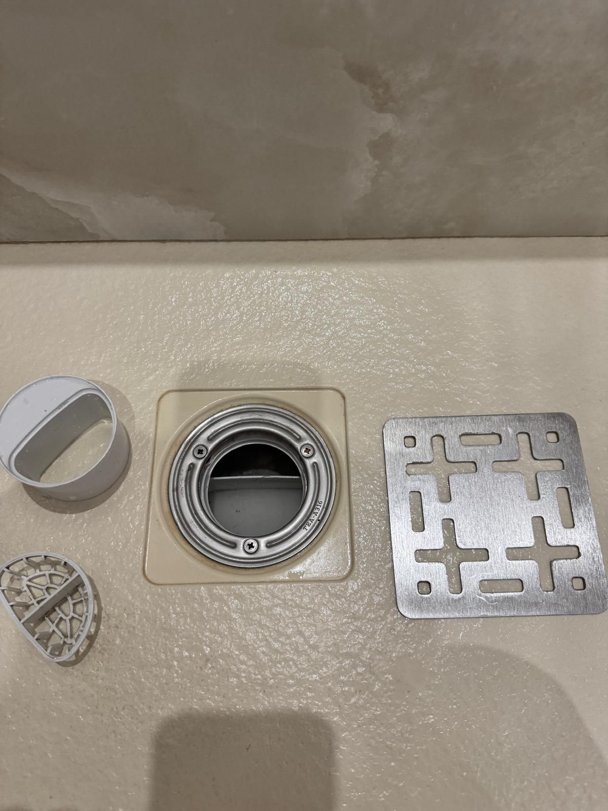 Parti di un gruppo di scarico: un telaio quadrato, uno scarico circolare con coperchio rimovibile e un pezzo curvo.