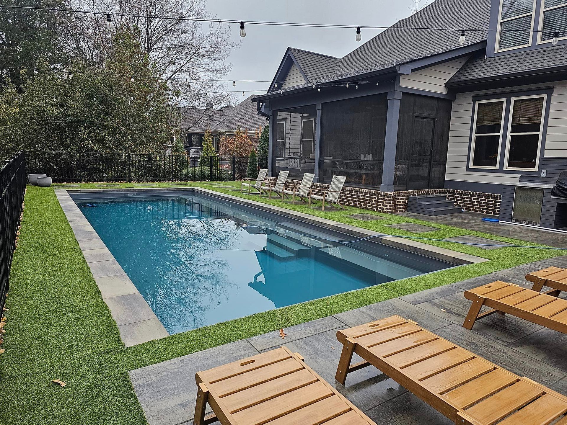 There is a large swimming pool in the backyard of a house.