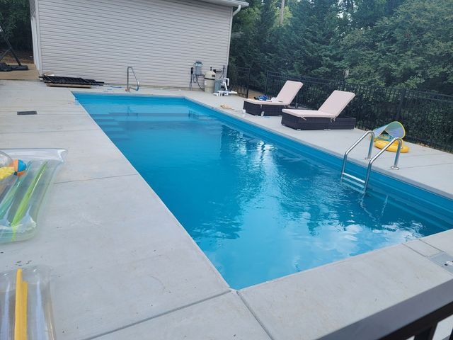 A large swimming pool surrounded by chairs and a house