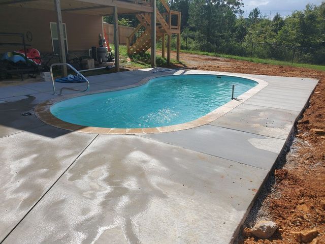 A swimming pool is sitting on top of a concrete patio next to a house.