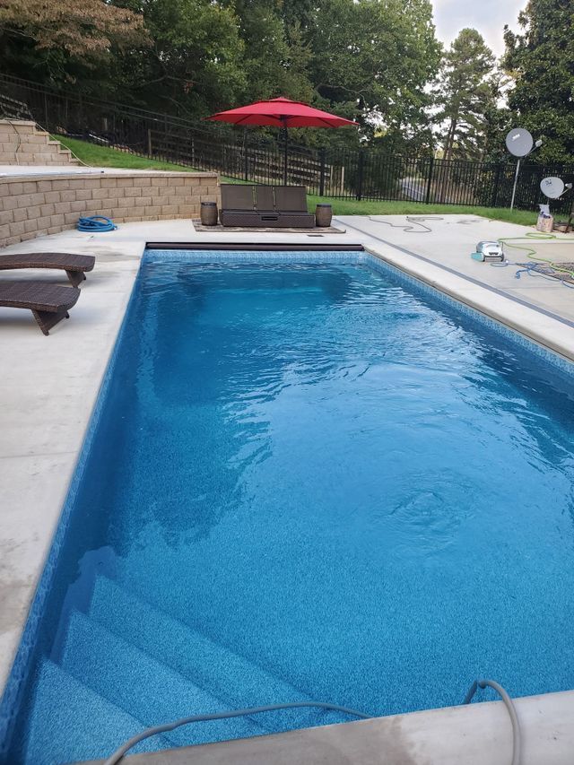 A large swimming pool with a red umbrella in the middle of it.