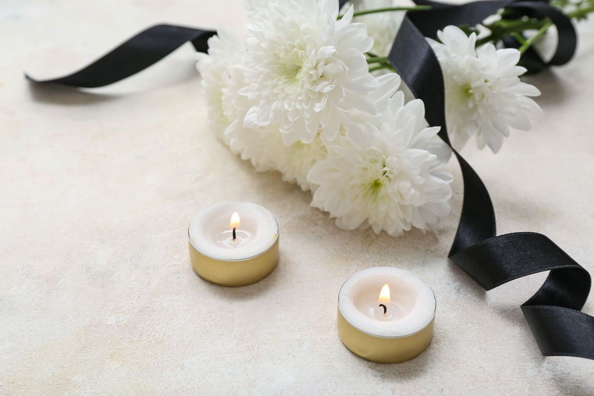 Chrysanthemum flowers with black funeral ribbon and burning candles