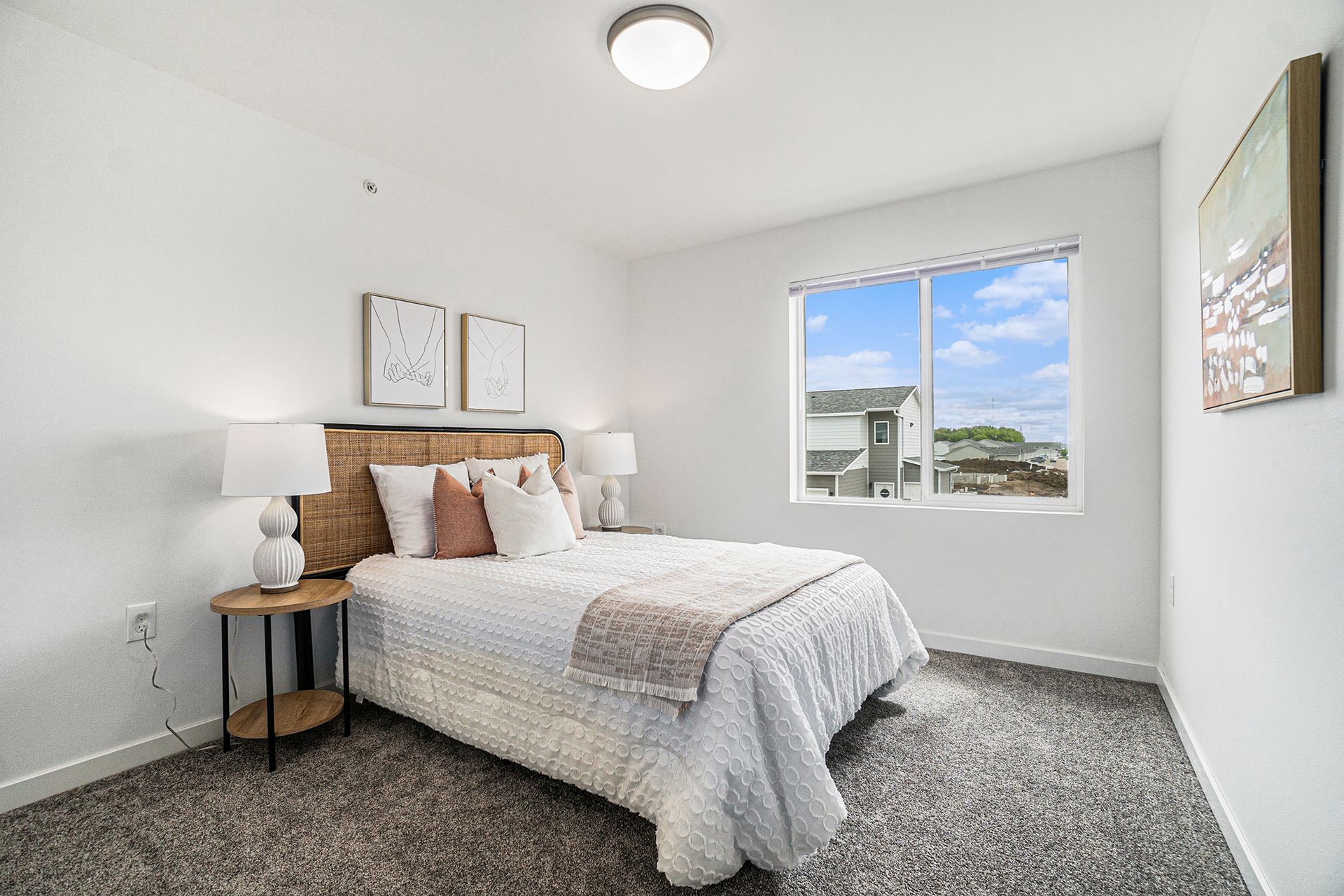 A bedroom with a bed , nightstand , lamps and a window.