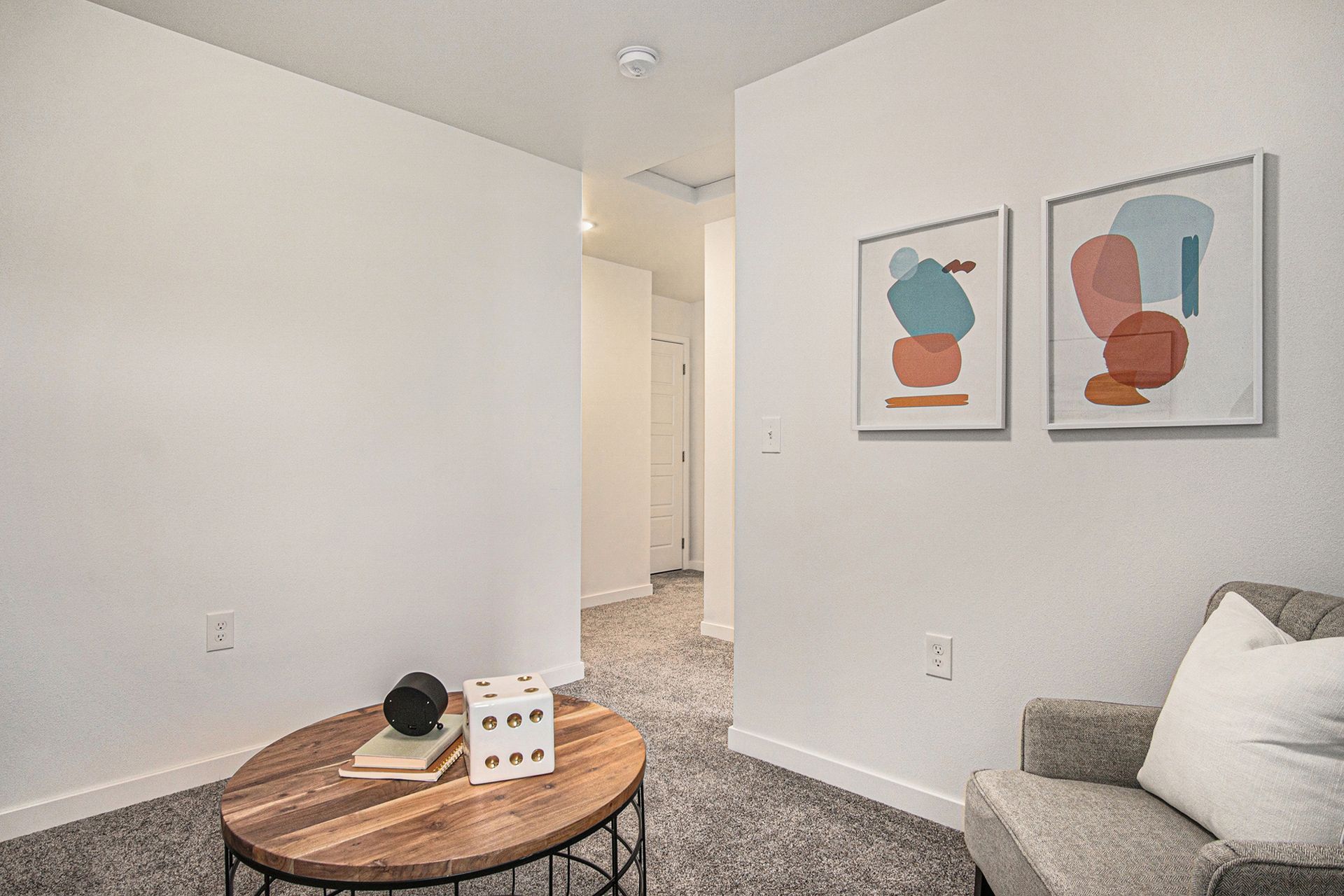 A living room with a chair , coffee table , and paintings on the wall.