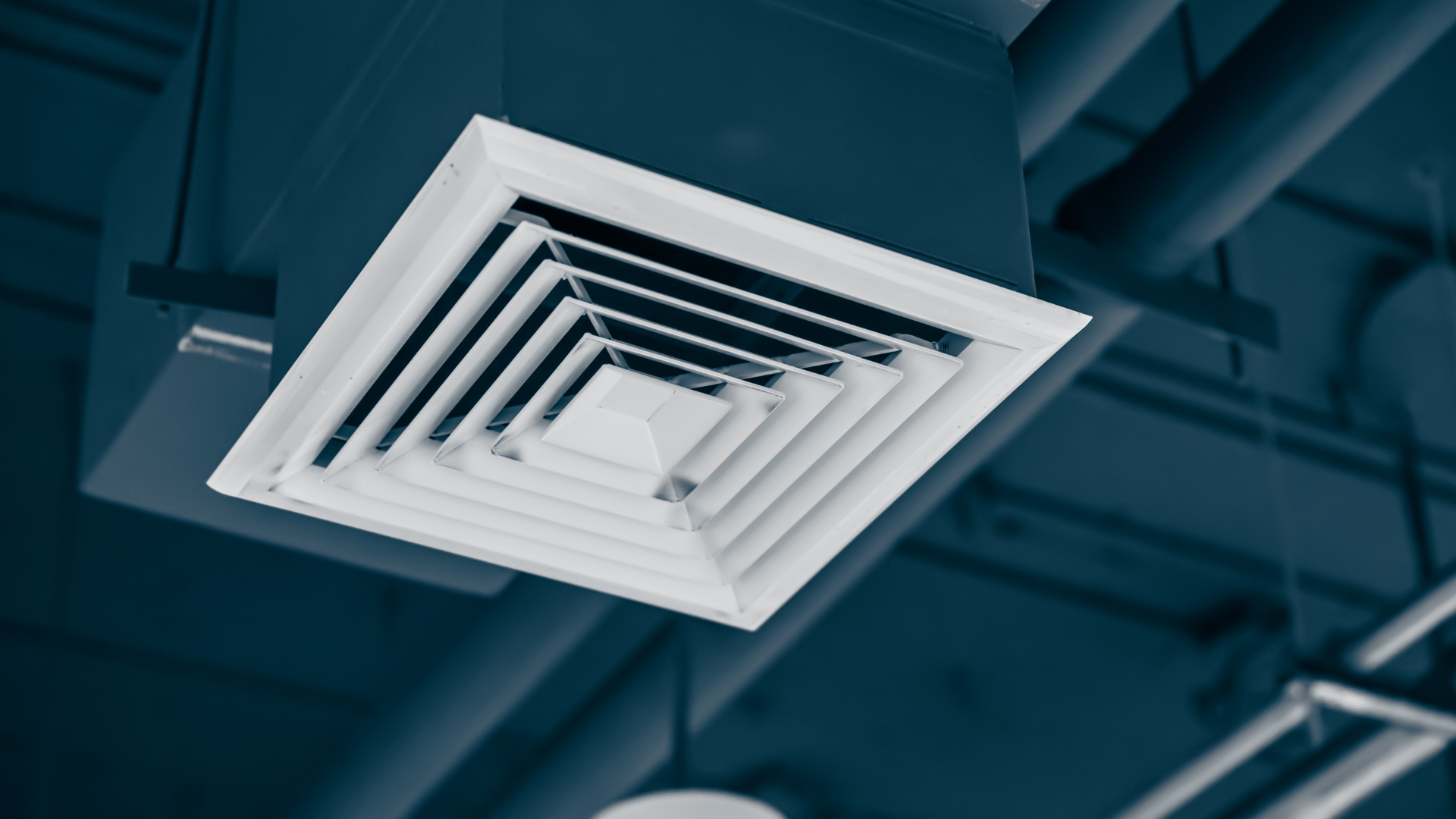 A square air vent is hanging from the ceiling of a building.