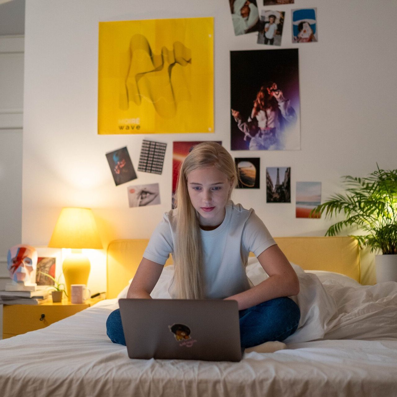 a girl is sitting on a bed using a laptop computer