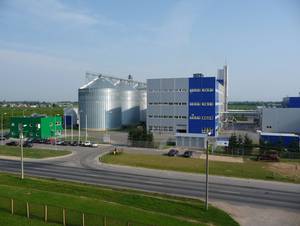 A large industrial building with a lot of silos and a road in front of it.