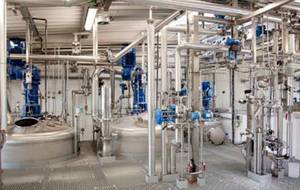 A large room filled with lots of pipes and tanks in a factory.