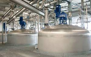 A factory filled with lots of stainless steel tanks and pipes.